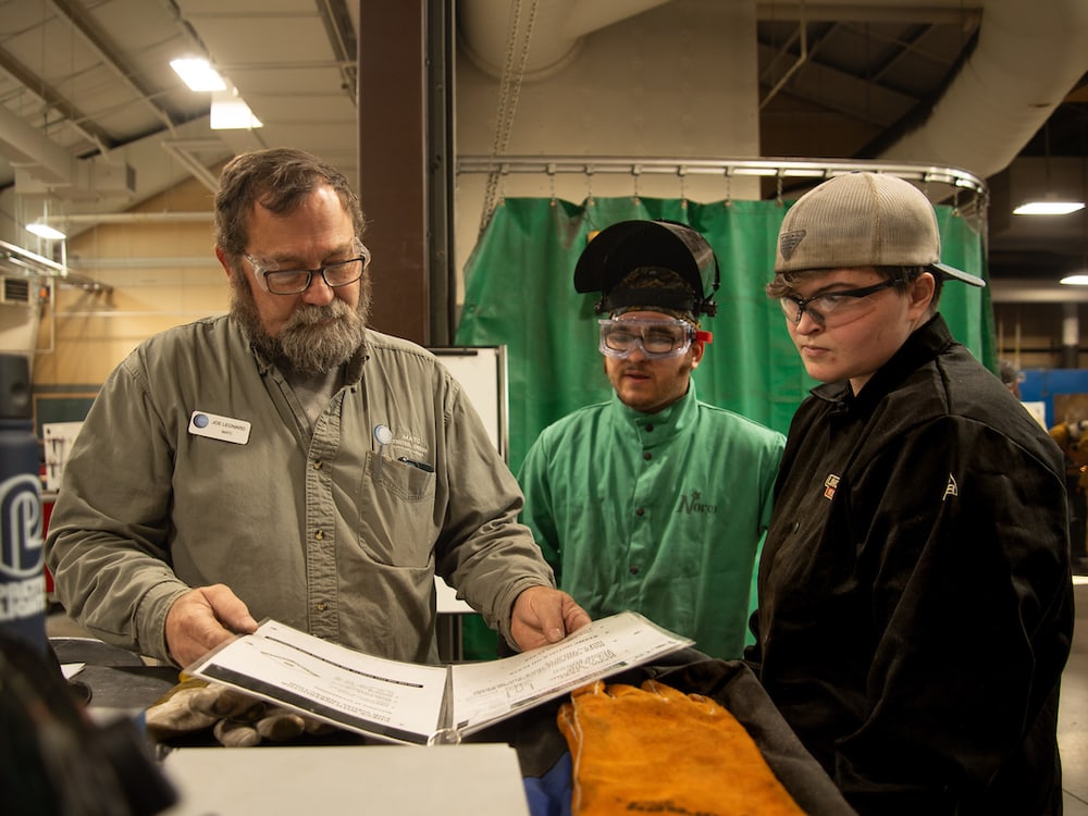 A COCC welding instructor reviewing a work plan with two students