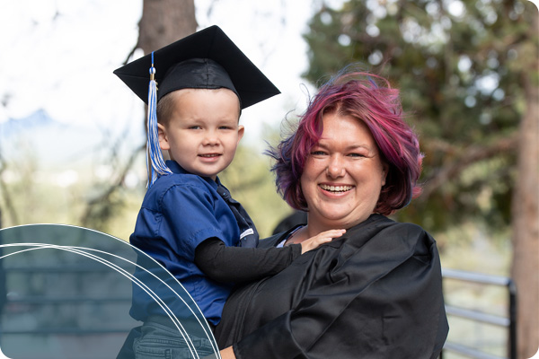 COCC graduate holding child wearing graduation cap