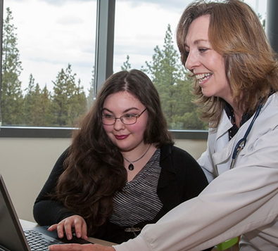 Student and teacher smiling at a computer screen