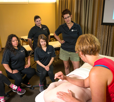Massage Therapy Instructor giving a demonstration to a group of students