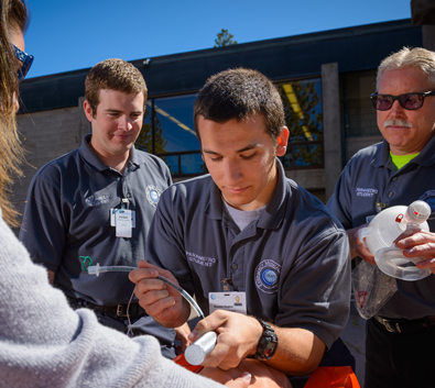 Paramedic students practicing a medical procedure outdoors