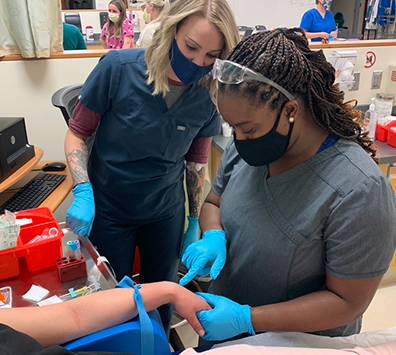 Healthcare students practicing drawing blood in a lab