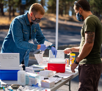Two people conversing at an outdoor public health table