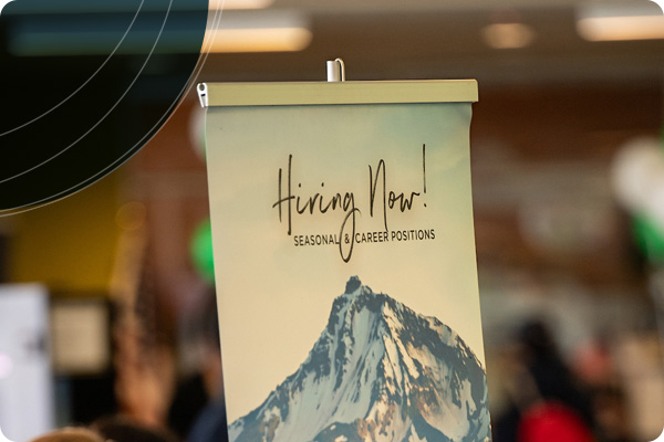 Sign that says 'Hiring Now, Seasonal and Career Positions' with Mt. Bachelor is the background