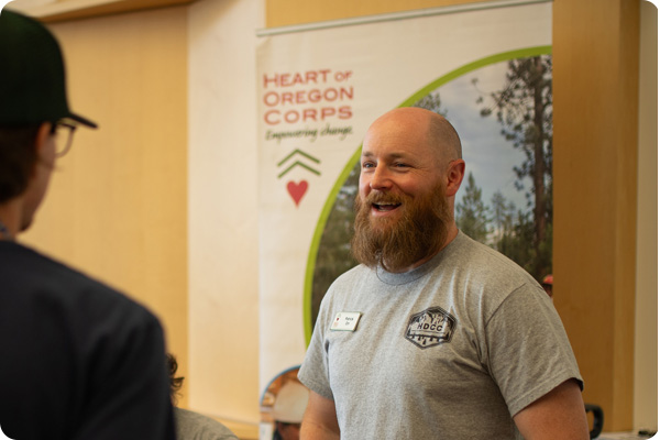 Person talking in front of 'Heart of Oregon Corps' sign