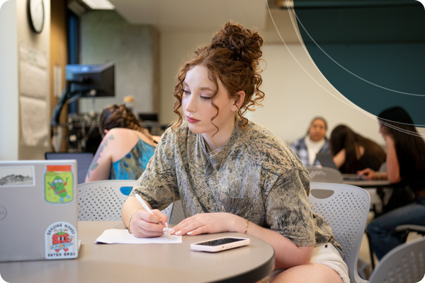 Student writing notes from a lecture on a laptop
