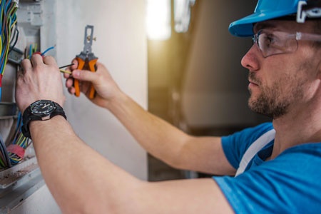 Man in blue hardhat works on an electrical panel