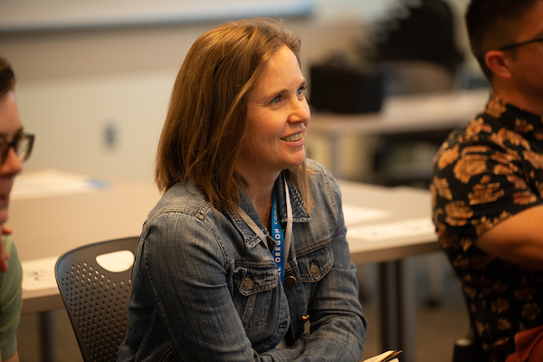 Woman in a chair listens to an instructor out of frame