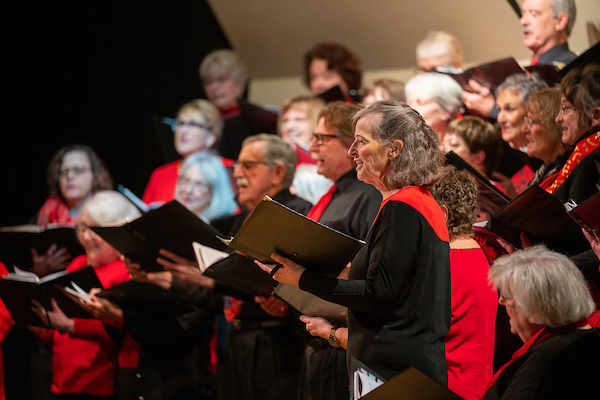 A community choir on stage sings to the audience
