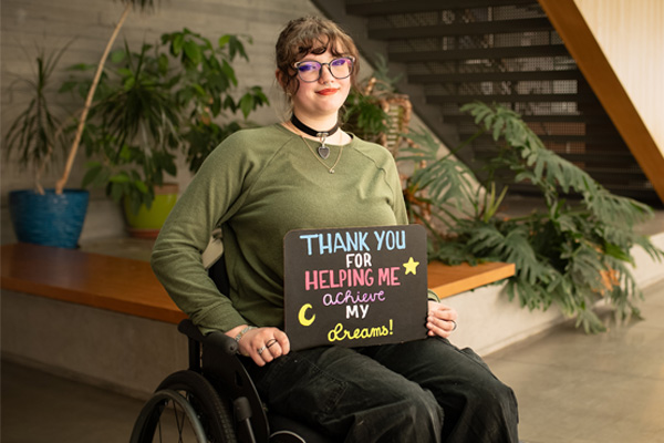 COCC student holding a sign that says "Thank you for helping me achieve my dreams"