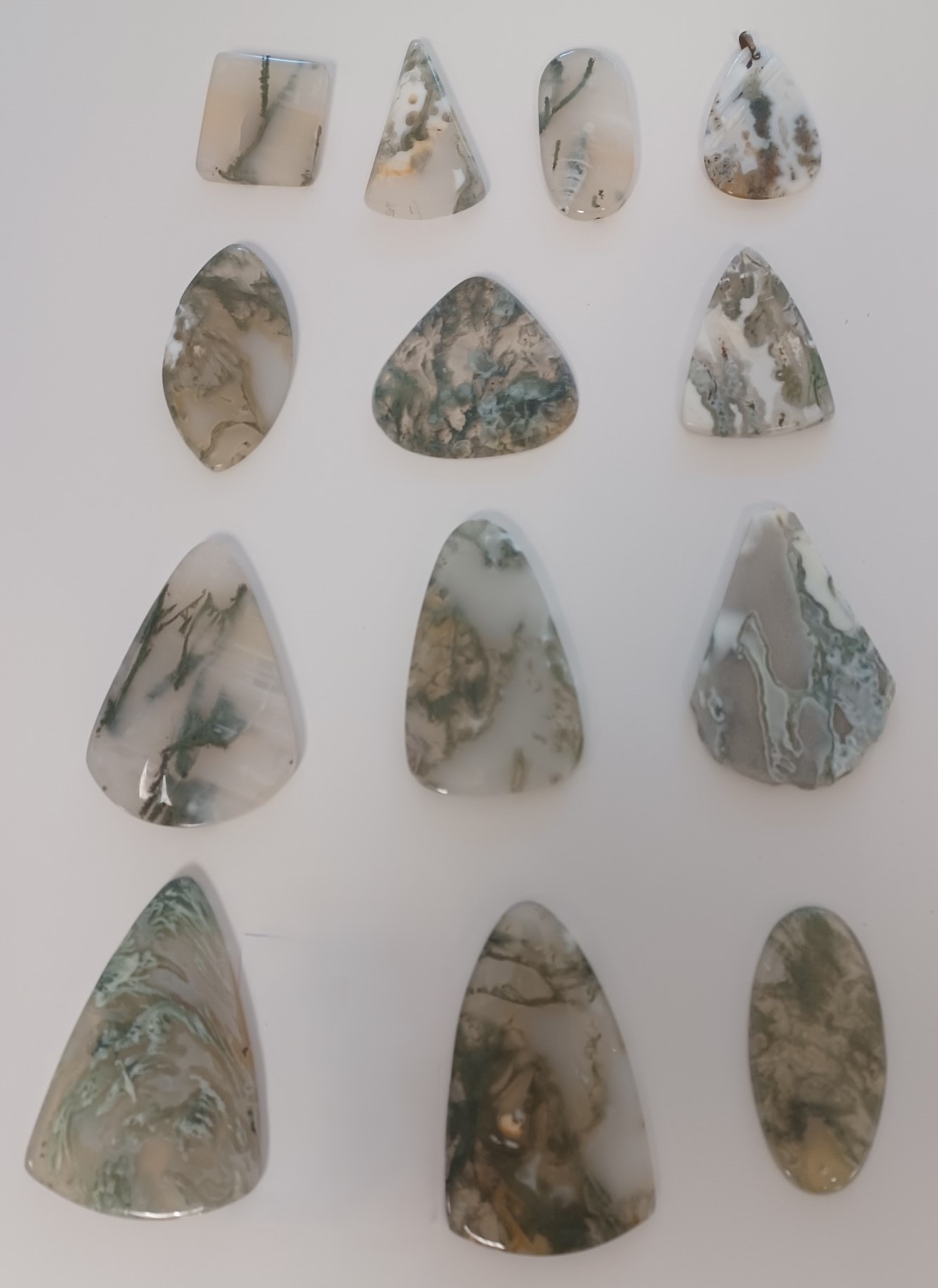 Polished agate. Largely white with inclusions of gray, green and brown.