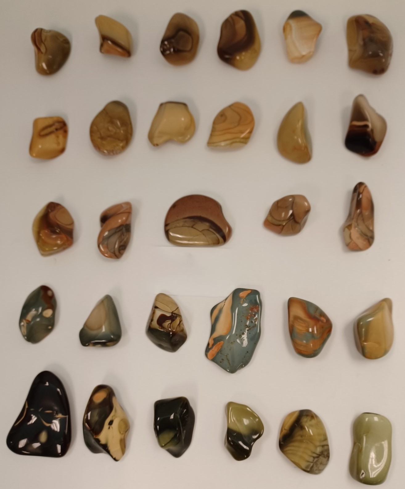 Variety of polished Jasper stones, ranging in colors from brown and beige to a blue-ish gray to green and black.
