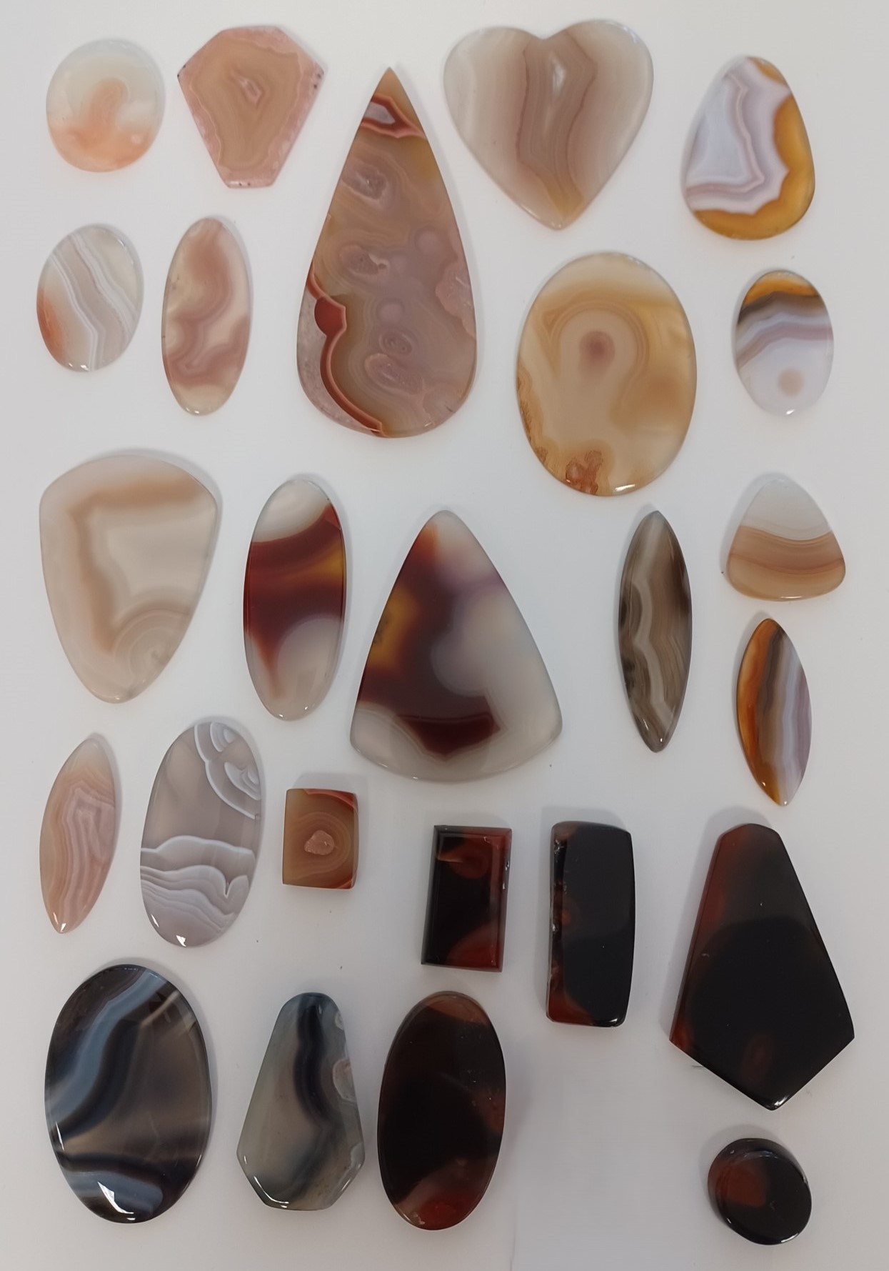Polished agate in colors of pink, white, brown, gray and black. One piece is heart-shaped.