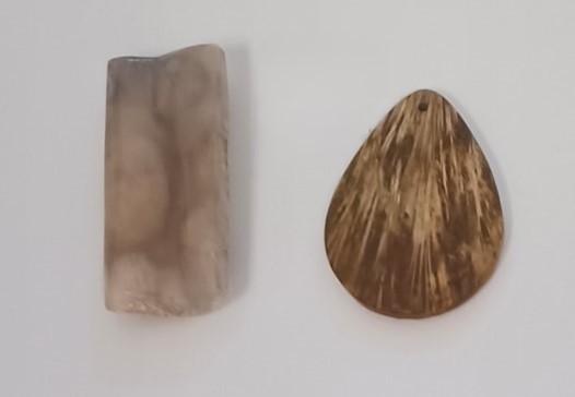 Two agates; one rectangular and mottled brown and white. The other resembles a clam shell and is brown and white. 