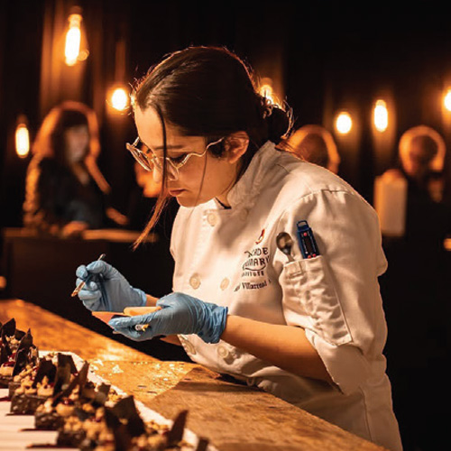 Culinary student adding finishing decorative touches to a desert