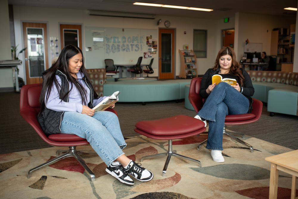 Two students reading in two chairs in the Student Commons