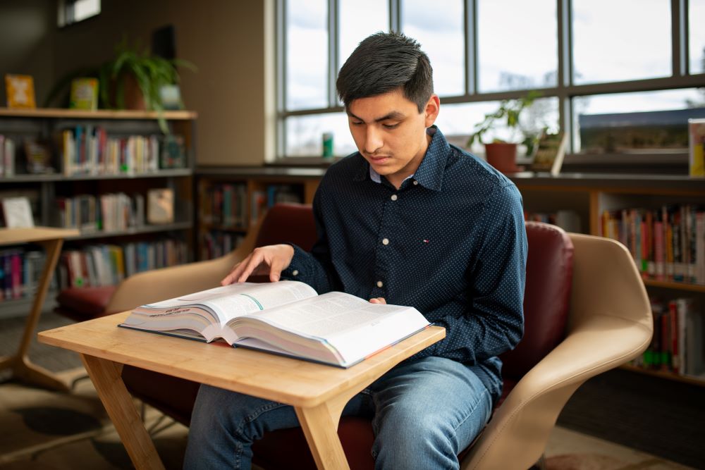 Student reading a textbook in the Student Commons.