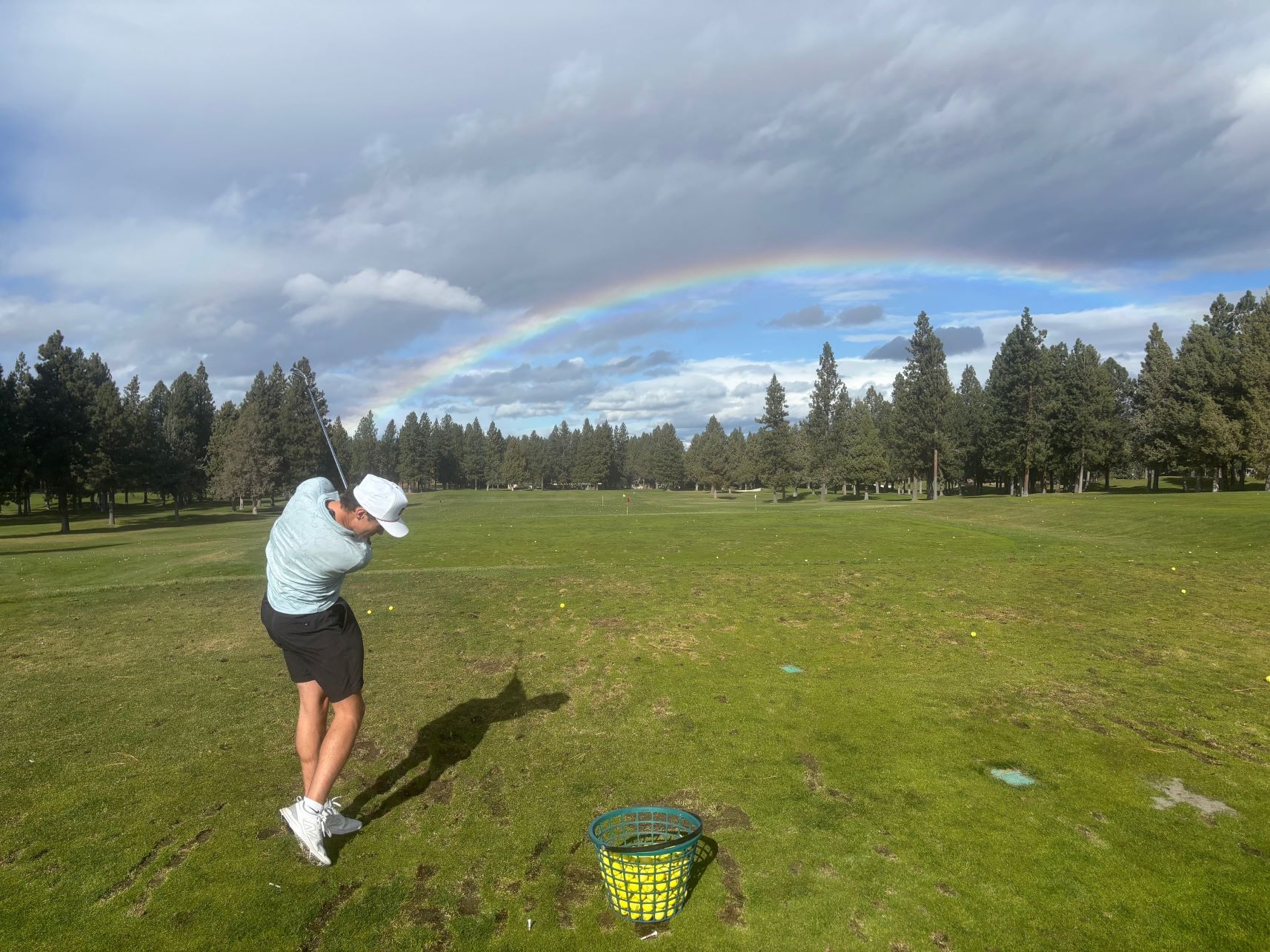 student golfing with rainbow in background