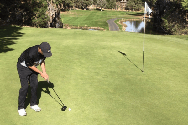 golfer putting on green into the hole with flag