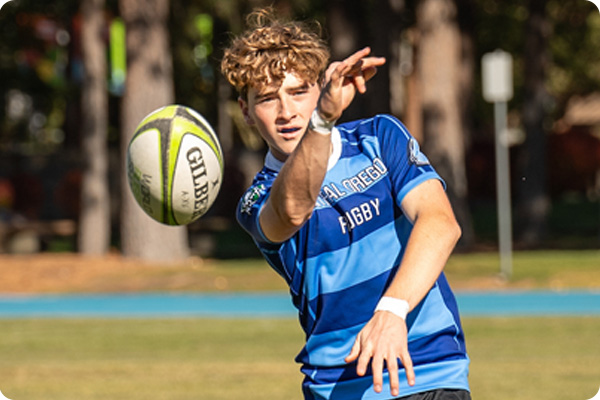 Rugby player tossing a rugby ball at the camera