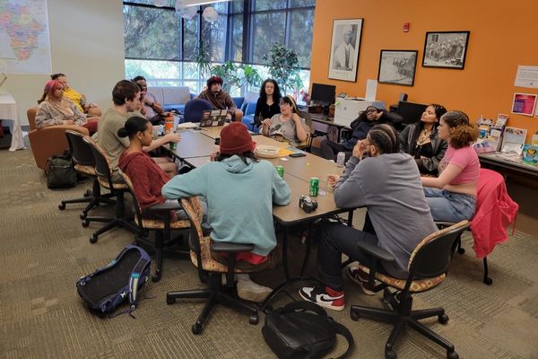 Group of students in the Afrocentric Club sitting around a table talking.