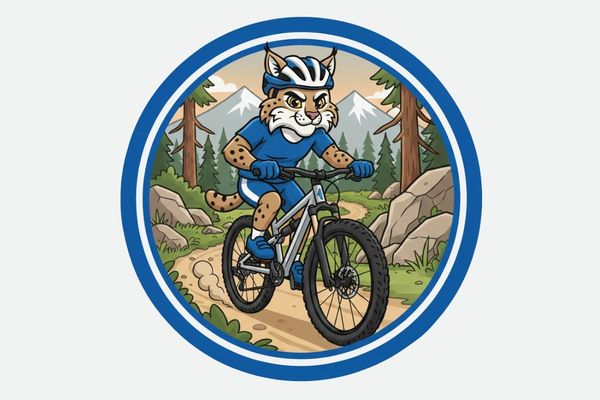 photo of bobcat mountain biking on a trail with mountains behind