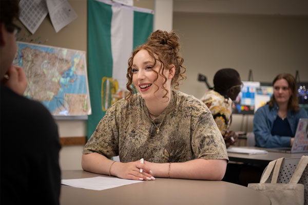 Person assembling a model skeleton on a table, arranging bones of the leg and foot with their hands.