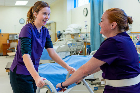 Healthcare students practice patient mobility techniques during hands-on clinical training.