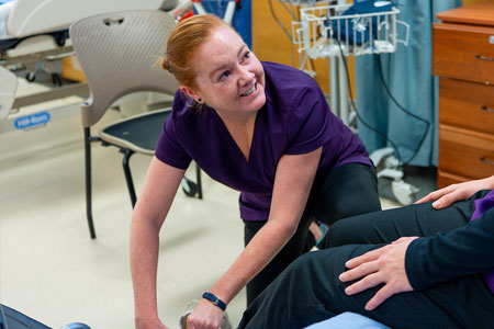 Healthcare student assists a seated patient during hands-on clinical training.