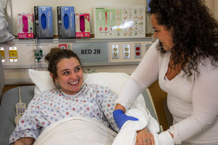 Caregiver provides bedside assistance to a patient in a hospital setting.