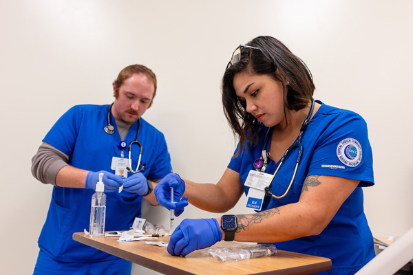 2 nursing students learning how to fill syringes