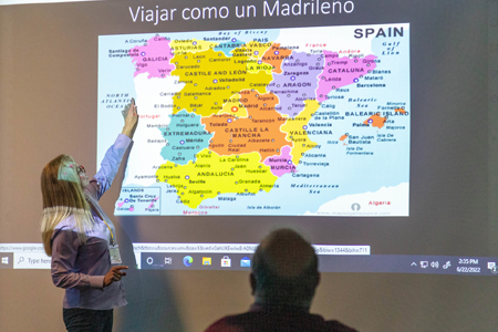 Community college world language instructor pointing at spain on a big map
